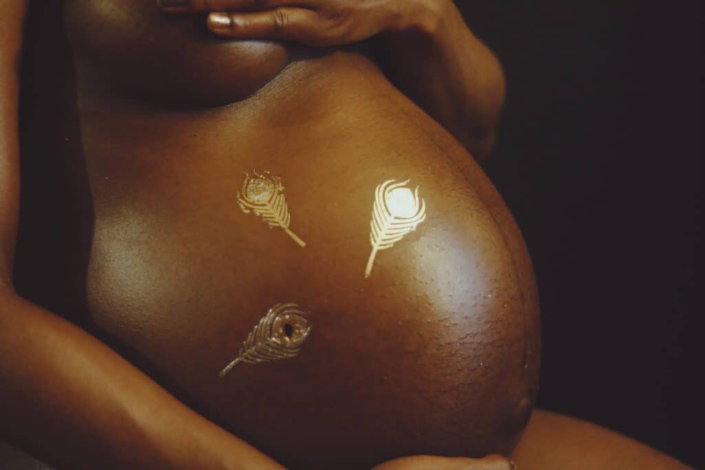 black woman's pregnant belly with gold etching on her tummy